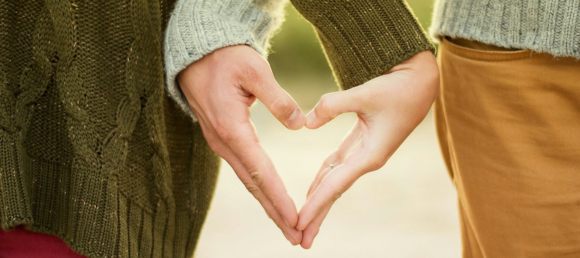 Two people form a heart shape with their hands.