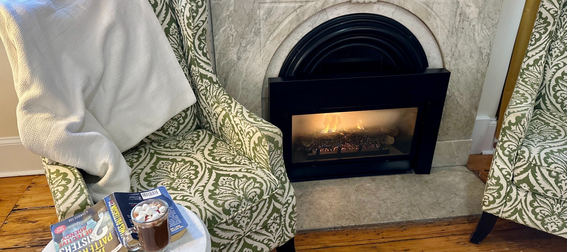 A chair with a blanket next to a roaring fireplace