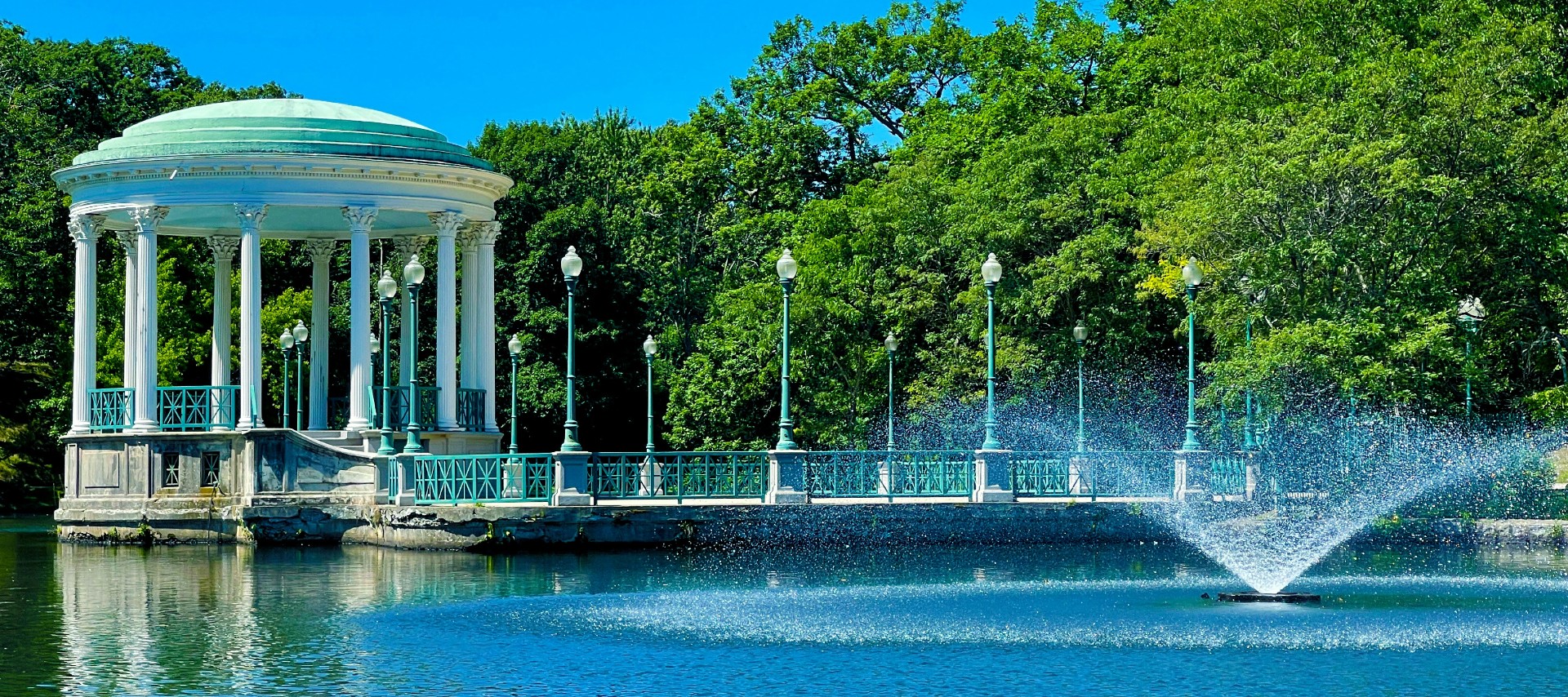 A gazebo in the middle of a pond surrounded by trees