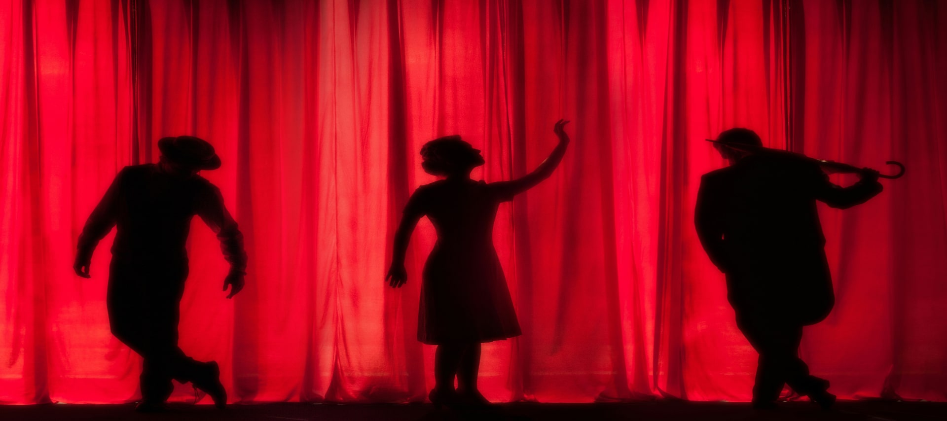 Silhouette of three performers on stage